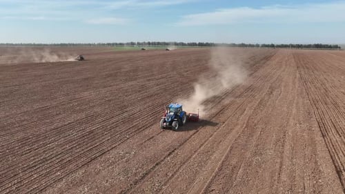 Tractors Plowing Vast Field in the Countryside