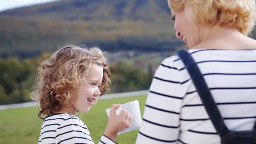 Une jolie petite fille avec sa mère à l'extérieur, des tasses