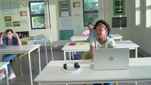 On teacher cue African American teen raising hand, placing laptop and headset, answering in class