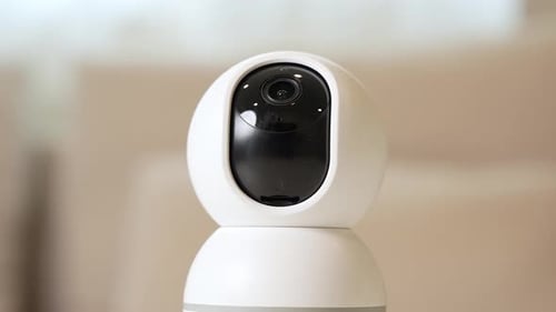 A close-up of a CCTV camera tilting down to monitor a home interior.