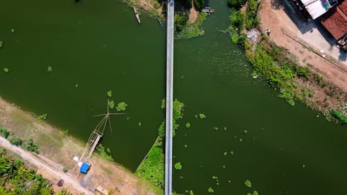 Aerial arc from top of green natural river with small bridge
