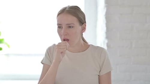 Young Woman Coughing Indoors, Mid Shot