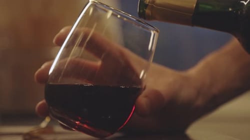 Man Pouring Red Wine On Glass. - close up
