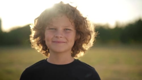 Boy with Curly Hair Smiling in Field