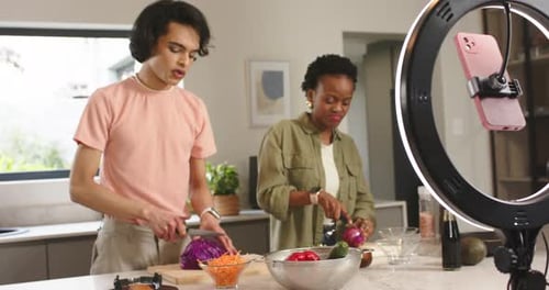Diversos coanfitriones entran en la cocina de su casa y cortan verduras con una luz anular para cocinar tutorial