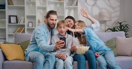 Familia feliz, padres adultos con lindos niños en edad escolar que usan aplicaciones de teléfonos inteligentes riendo