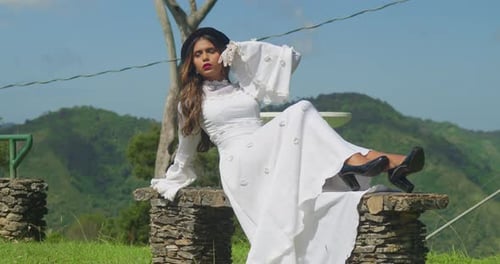 A girl in an elegant, old-fashioned wedding dress walking through a deserted fort.