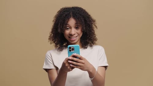 Smiling woman interacting with her smartphone indoors