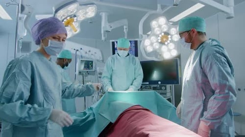 Gleitaufnahme eines vielfältigen Teams professioneller Chirurgen, die einen invasiven Eingriff an einem Patienten in t durchführen