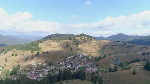 AERIAL: a small village in a valley between hills.