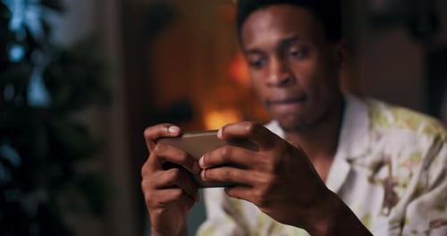 Man Playing Game on Mobile Phone at Home