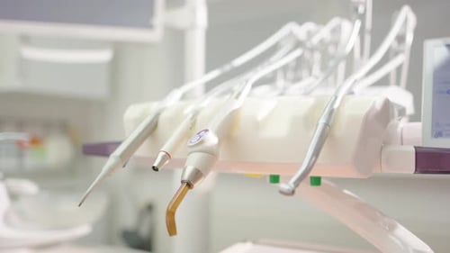 Hygienic metal dental tool is put down amongst others in clinic, closeup slider