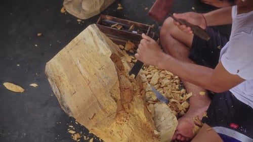 Man Carving Wooden Sculpture with Chisel and Mallet