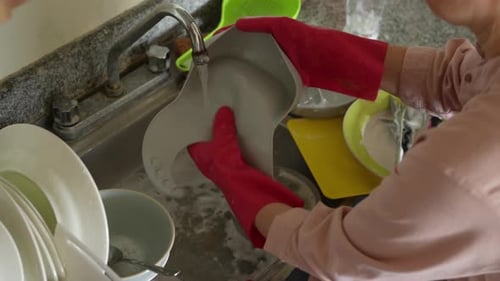 Adult Washing Dishes in Kitchen Sink
