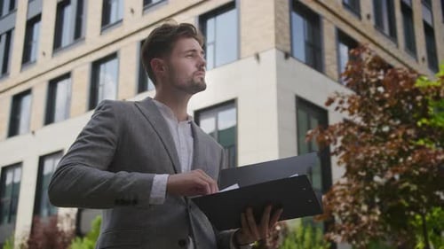 Focused Executive Reviewing Documents Outdoors