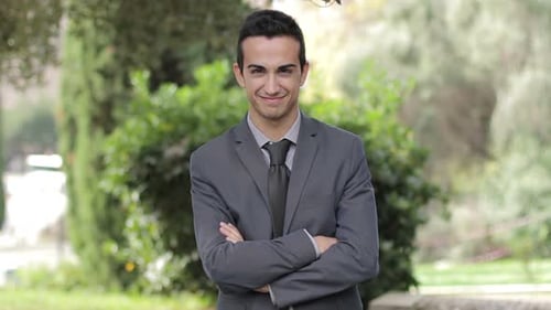 Satisfied smiling young businessman In the park