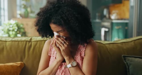Woman, sneeze and tissue on couch in home, sick and sinusitis with flu, allergy