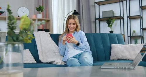Smiling Woman Using Smartphone on Couch at Home