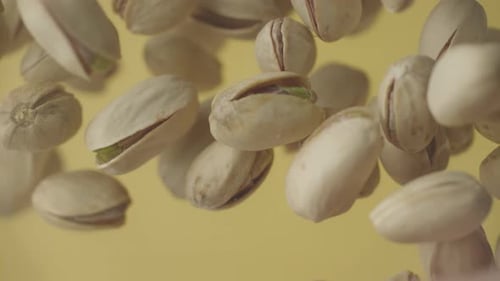 Pistachios Falling in Slow Motion on Tan Background