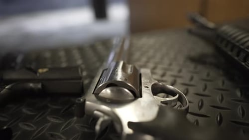 Primer plano de un revólver con empuñadura negra sobre una mesa en un campo de tiro