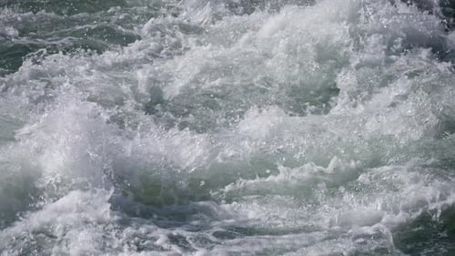 Nahaufnahme eines rasanten Gebirgsflusses aus türkisfarbenen Farbspritzern in Zeitlupe