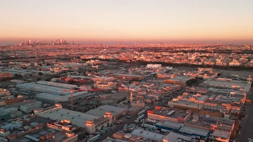 Drone aerial sunset city skyline over industrial district, golden hour metropolis panorama