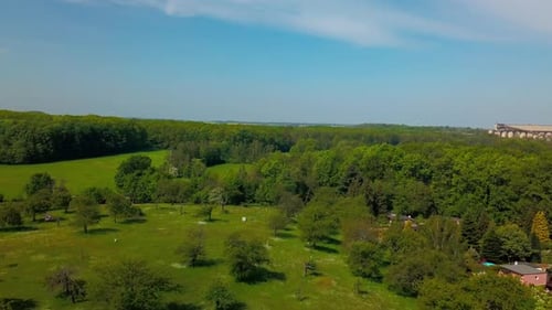 Aerial view of little village in between meadows and forest during spring or summer time