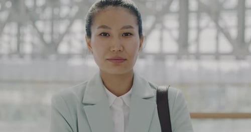 Portrait of Attractive Asian Woman Commuter Standing in Airport Lobby and Looking at Camera with