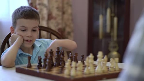 Boy Playing Chess Indoors at a Table