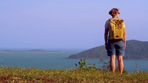 Woman Standing on Hill with Yellow Backpack Looking at Ocean Horizon and Tropical Islands, Traveler