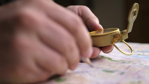 Male hands using compass on colorful map
