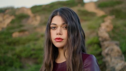 Portrait of Gentle Young Brunette Touching Long Hair in Front Green Hill