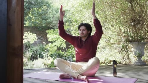 Caucasian man practicing yoga meditation on terrace in sunny nature, slow motion