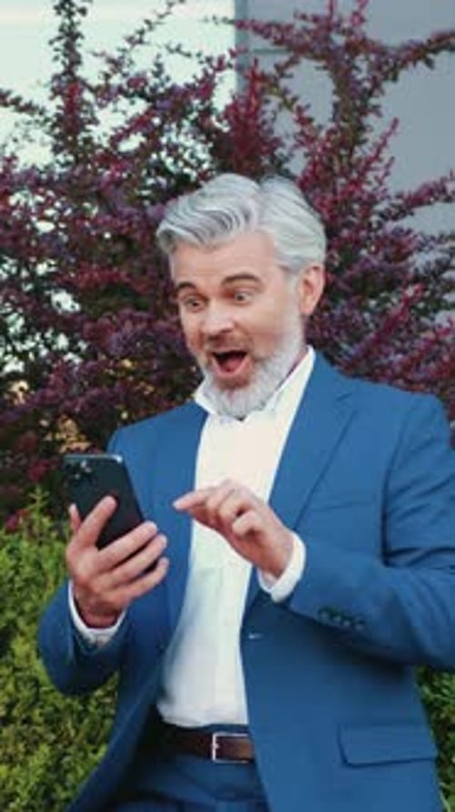 Excited Man in Suit Looking at Phone
