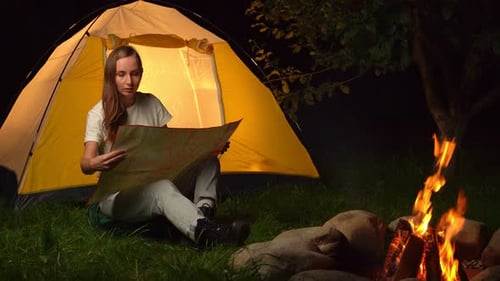 Woman Planning Adventure Trip by Campfire at Night