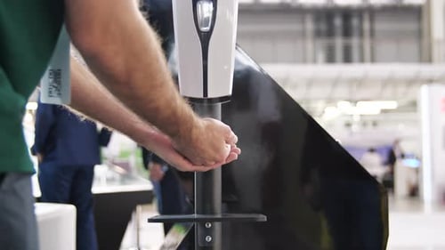 Businessman Sanitizing Hands with Automatic Dispenser
