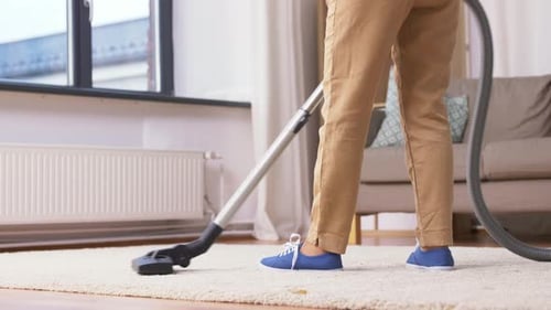 Adult vacuums light rug in bright living room