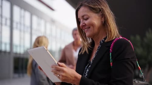 Mature Caucasian Business Woman Worker in Formal Suit Smiling Using Tablet Standing Outside Office