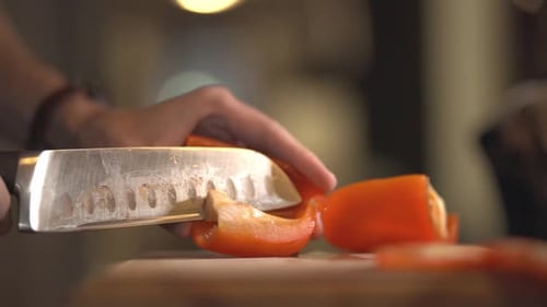 Removing The Seeds Of A Red Capsicum Using A Sharp Knife Over The Wooden Board. -close up shot