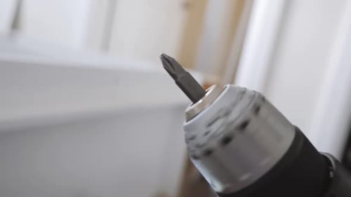 Close up of a drill slowly spinning in the air with a white background.