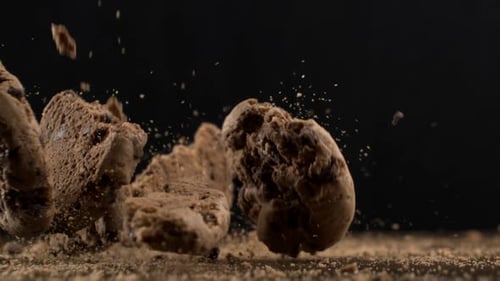 Super Slow-Motion Macro Close-Up of many Chocolate Chips Falling onto Table with Crumbs