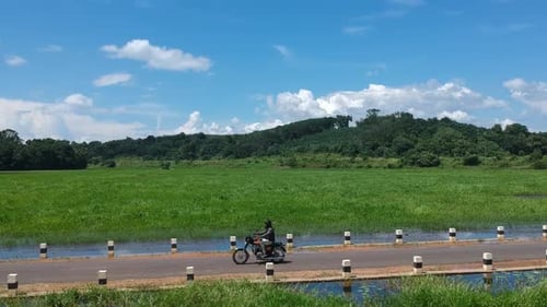 Motorbike rider on Indian village road,Bike Rider,Road between river,beautiful Sky