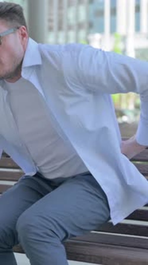 Man Sitting on Bench Experiences Sudden Back Pain