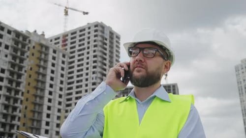 Bearded building contractor talking on phone at construction site