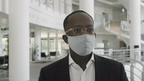 Businessman wearing face mask and walking in office lobby on way to meeting
