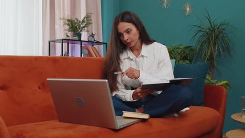Woman Working at Home on Laptop Taking Notes