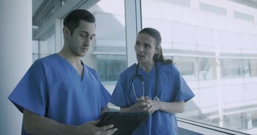Medical Professionals Discussing Patient Data in Hospital Corridor