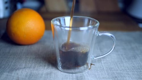Slow motion of black coffee pouring down a transparent Italian espresso cup on a piece of grey cloth