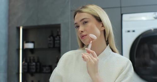 Woman Using Facial Roller in Bathroom