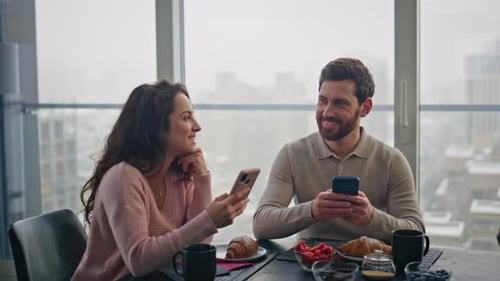 Couple Using Smartphones at Breakfast Table Indoors